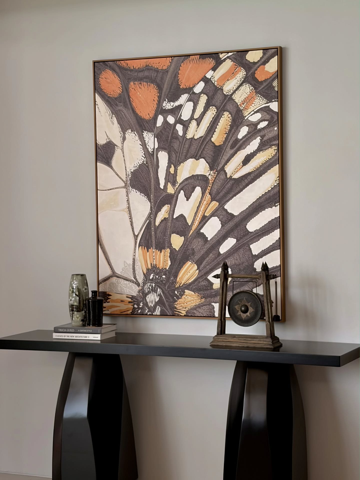 Botanica butterfly artwork above a black console